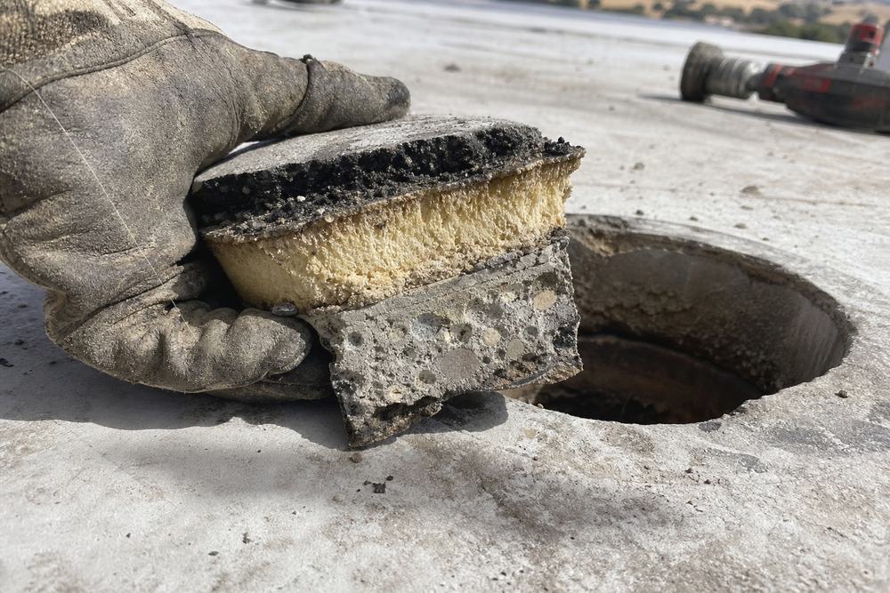 Core cut sample showing the membrane, insulation and deck layers of a commercial roof